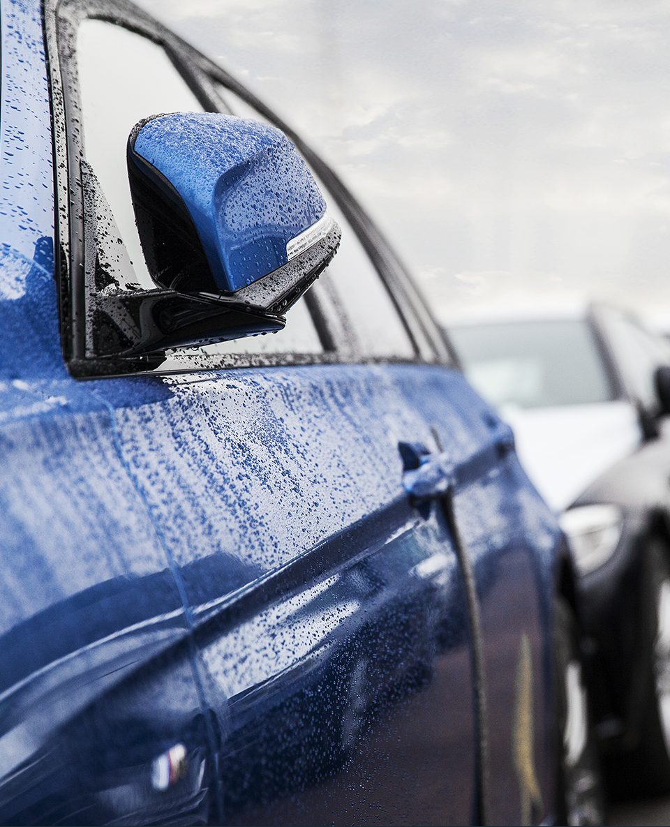 En regnblöt blå bil ute på gården.