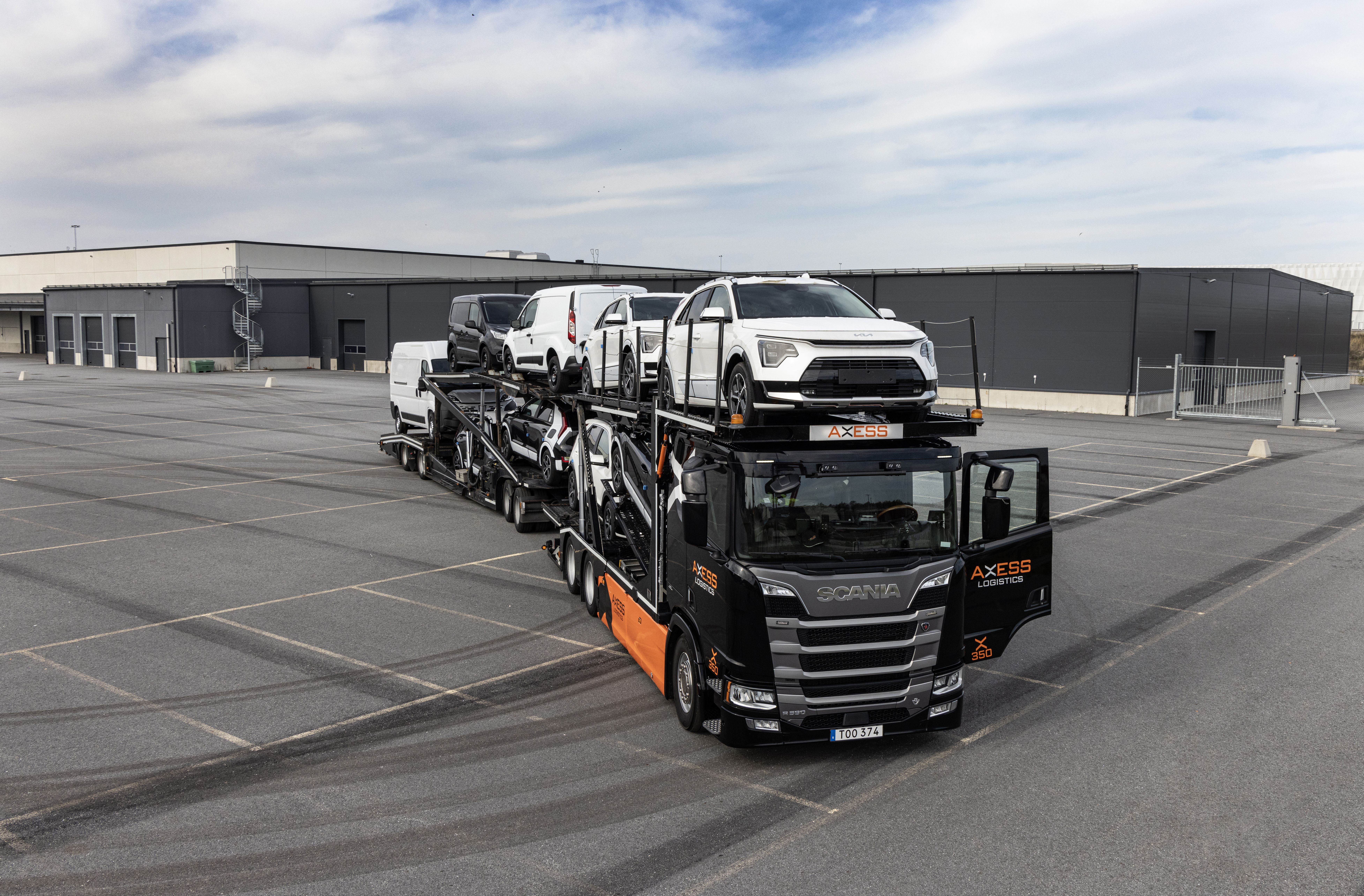 Biltransport lastad med personbilar på en stor parkering.